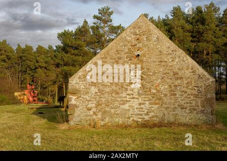 Un bâtiment de ferme semi-restauré avec quelques Outils et outils de ferme anciens, situé dans un pré au bord de la forêt de la Réserve naturelle de Crombie Banque D'Images