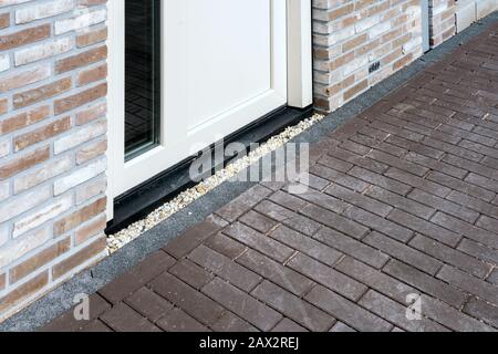 Gros plan sur la porte moderne blanche avec façade en brique et pavés sur le sentier. Banque D'Images