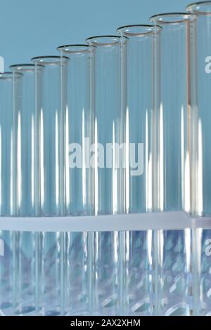 Image verticale des tubes à essai transparents retirés dans le plateau sur fond bleu. Banque D'Images