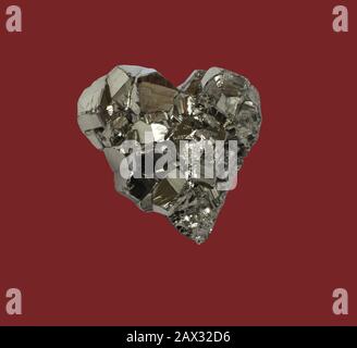 Pyrite minérale en forme de coeur sur fond rouge foncé Banque D'Images