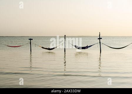 Détendez-vous dans un hamac au-dessus de l'eau au coucher du soleil, Isla Holbox, Mexique Banque D'Images