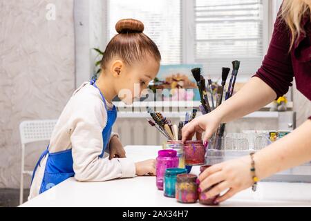 Master class dans le studio Ebru - l'art de la "peinture sur l'eau." la femme enseignante met des peintures et des outils devant la fille. Banque D'Images