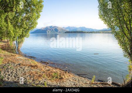 Lever du soleil du lac tôt le matin avec lumière dorée. Ciel bleu et eau. Lac Wanaka Nouvelle-Zélande, destination De voyage Populaire. Banque D'Images