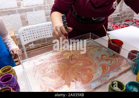 Master class dans le studio Ebru - l'art de "peindre sur l'eau." l'enseignant féminin montre fille à l'aide d'outils, les mains près. Banque D'Images