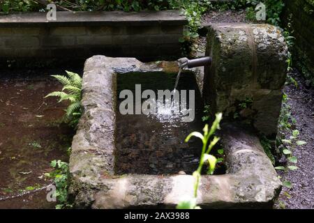 Ancien réservoir d'eau potable rustique avec de l'eau fraîche qui coule dans Banque D'Images