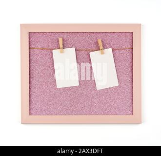 cadre rose brillant avec cordes et feuilles de papier blanc vides accrochées sur des clothespins en bois, place pour photo et inscription Banque D'Images