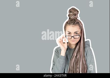 Belle fille stricte avec des piquets roses zizi abaissé ses verres et regarde derrière eux à l'appareil photo sur un fond gris avec un trait ou un cadre. Con Banque D'Images