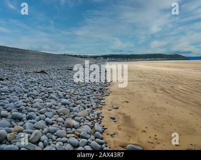 Galets gris de la crête de galet naturellement formée et de la plage de sable de Westward Ho à Devon, Royaume-Uni, pris une journée ensoleillée en été Banque D'Images