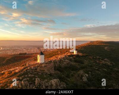 Moulins à vent de Campo de Criptana sur une colline couverte Verdure au coucher du soleil en Espagne Banque D'Images