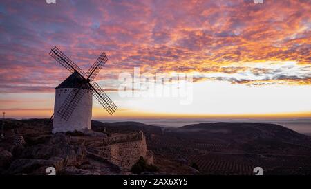 Moulin de Campo de Criptana entouré de collines sous un Ciel nuageux au coucher du soleil en Espagne Banque D'Images