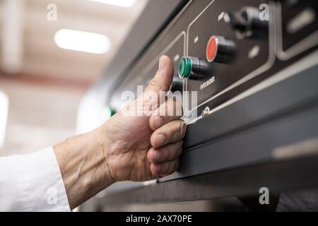 Gros plan sur le bouton-poussoir du conducteur de la machine non reconnaissable lors du lancement de la chaîne de production en usine Banque D'Images