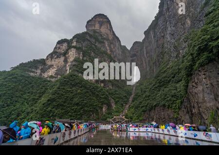 Zhangjiajie, Chine - Août 2019 : foules de touristes Massives attendant dans la pluie torrentielle mousson pour les mini-bus de transport public au pied de Tianmen M Banque D'Images