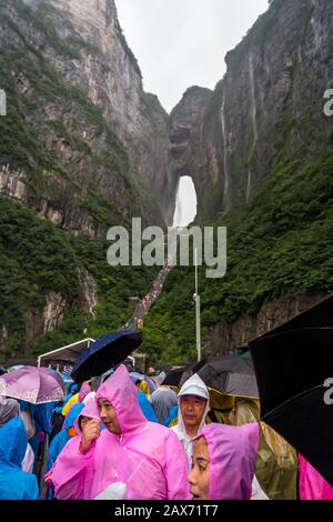 Zhangjiajie, Chine - Août 2019 : foules de touristes Massives attendant dans la pluie torrentielle mousson pour les mini-bus de transport public au pied de Tianmen M Banque D'Images