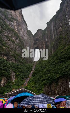 Zhangjiajie, Chine - Août 2019 : foules de touristes Massives attendant dans la pluie torrentielle mousson pour les mini-bus de transport public au pied de Tianmen M Banque D'Images