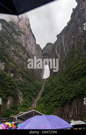 Zhangjiajie, Chine - Août 2019 : foules de touristes Massives attendant dans la pluie torrentielle mousson pour les mini-bus de transport public au pied de Tianmen M Banque D'Images