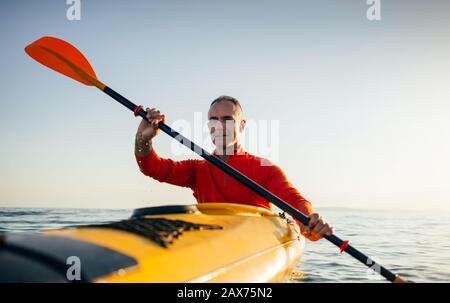 Homme senior actif paddling kayak. Faites du kayak de mer Banque D'Images