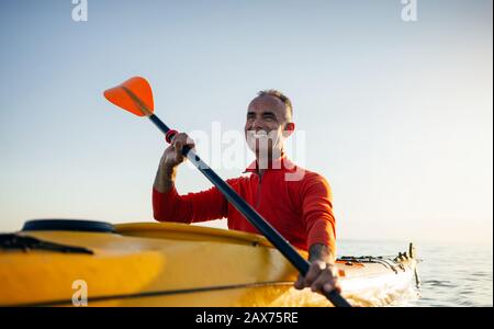 Homme senior souriant pagayant en kayak Banque D'Images
