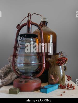 Toujours la vie avec une ancienne lampe au kérosène, une grande bouteille et un pichet avec une bande d'herbe de rowan. Vintage. Rétro. Banque D'Images