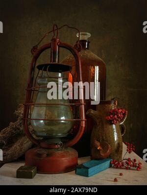 Toujours la vie avec une ancienne lampe au kérosène, une grande bouteille et un pichet avec une bande d'herbe de rowan. Vintage. Rétro. Banque D'Images