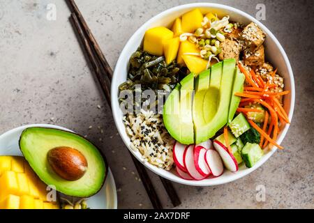 Poke bol végétalien avec avocat, tofu, riz, algues, carottes et mangues. Concept de nourriture végétalienne. Banque D'Images