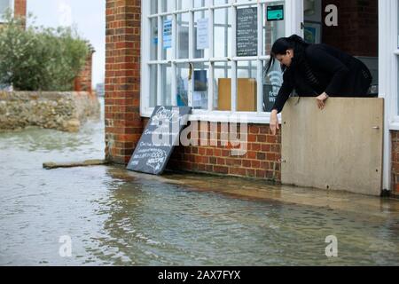 Bosham, West Sussex. 10 février 2020. Météo au Royaume-Uni : un employé de café fixe les barrières en place à mesure que les marées montent à la suite de la tempête Ciara et inondent le village de Bosham, West Sussex, Royaume-Uni lundi 10 février 2020. De nombreux endroits au Royaume-Uni sont toujours équipés d'avertissements météorologiques jaunes alors que le front de temps de Storm Ciara se poursuit. Photo : Luke Macgregor Crédit : Luke Macgregor/Alamy Live News Banque D'Images