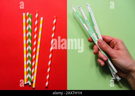 Pailles de papier contre pailles de plastique sur fond rouge et vert Banque D'Images