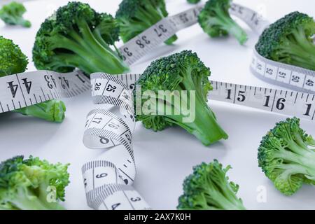 Fleurets de brocoli sur fond blanc avec ruban de mesure blanc entrelacé entre, concept de régime alimentaire Banque D'Images