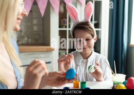 Joyeux petit garçon porté dans des oreilles de lapin se préparant à Pâques et à peindre des œufs. Gros plan portrait- image Banque D'Images