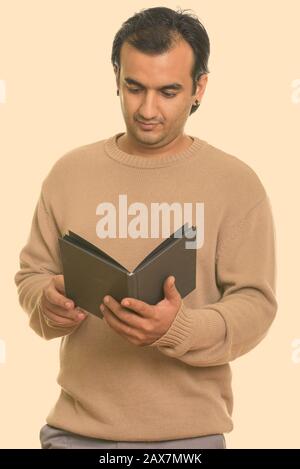 Studio shot of Persian man reading book Banque D'Images