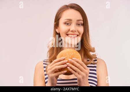 Fille doucement sourire blanc neige mange délicieux hamburger Banque D'Images