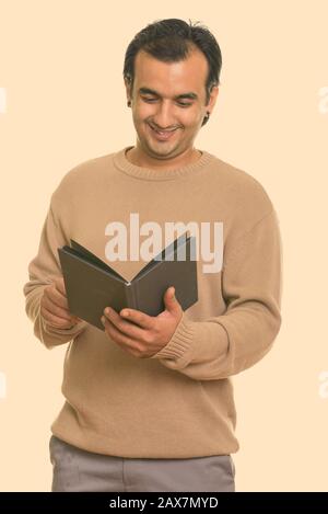 Studio shot of Persian man smiling and reading book Banque D'Images