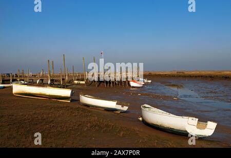 Petits bateaux et vieux quai près de creek à basse eau sur la côte nord de Norfolk à Morston, Norfolk, Angleterre, Royaume-Uni, Europe. Banque D'Images