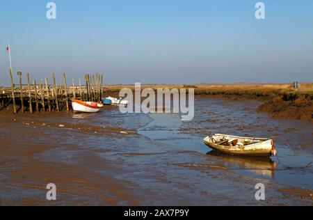 Petits bateaux dans un ruisseau marécageant dans les marais salés à marée basse sur la côte nord de Norfolk à Morston, Norfolk, Angleterre, Royaume-Uni, Europe. Banque D'Images