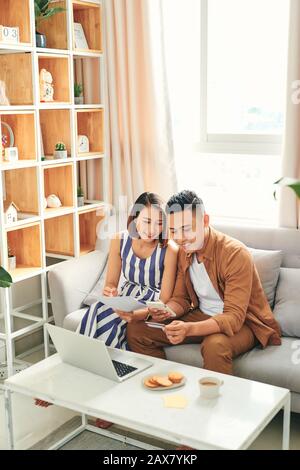 Jeune couple asiatique de vérifier la facture et payer en ligne avec carte de crédit. Banque D'Images