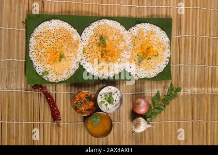 Les dosas épaisses et spongieuses ont servi avec le chutney de noix de coco et le sambhar sur la feuille de banane Banque D'Images