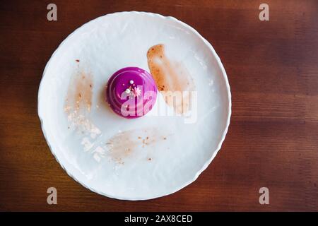 Gâteau avec glaçage rose coulé de remplissage en noyer. Sur une assiette blanche, debout sur la table. Banque D'Images