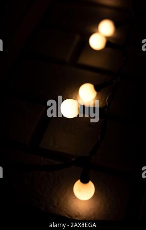 Ampoules lumineuses d'une guirlande sur un fond de mur de briques Banque D'Images