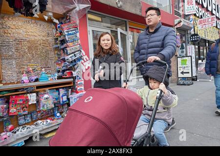 Les parents qui poussaient une poussette pour deux sur Main Street à Chinatown, Flushing, Queens, New York. Banque D'Images