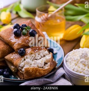 Crêpes fines avec fromage cottage et fraises. Concept de petit déjeuner traditionnel sain. Cuisson pour un carnaval russe traditionnel au printemps, Maslenitsa. Espace de copie. Banque D'Images