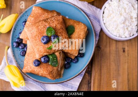 Crêpes fines avec fromage cottage et fraises. Concept de petit déjeuner traditionnel sain. Cuisson pour un carnaval russe traditionnel au printemps, Maslenitsa. Espace de copie. Banque D'Images