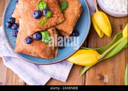 Crêpes fines avec fromage cottage et fraises. Concept de petit déjeuner traditionnel sain. Cuisson pour un carnaval russe traditionnel au printemps, Maslenitsa. Espace de copie. Banque D'Images