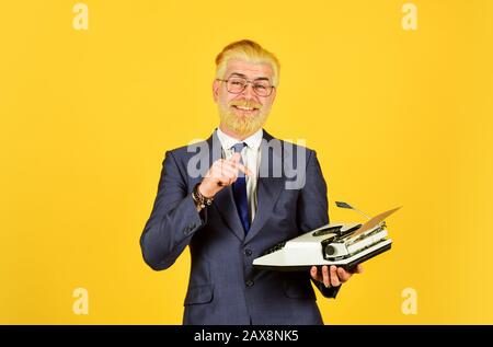 Homme mûr teint les cheveux de barbe fond jaune. Les vieux habitudes de l'auteur de bâton. Magasin de marchandises d'occasion. Objets anciens du vendeur. Connaisseur des valeurs vintage. Machine à écrire vintage. Les hommes d'affaires utilisent la technologie rétro. Banque D'Images