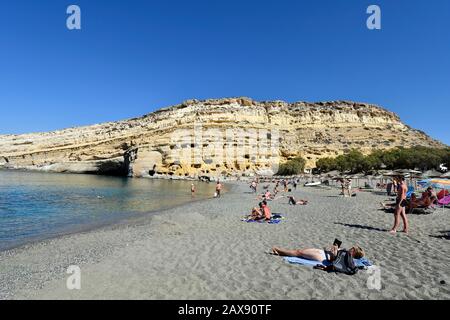 Matala, Grèce - 07 octobre 2018 : personnes non identifiées sur la plage de sable avec des tombes anciennes sur la colline Banque D'Images