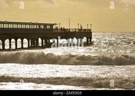 Boscombe, Bournemouth, Dorset England, Royaume-Uni, 11th février 2020, Météo : vents forts avec soleil et ciel orange le matin, tandis que la tempête Ciara passe. Les gens brave les éléments à la fin de la jetée. Banque D'Images