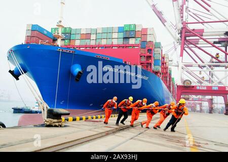 Les travailleurs portuaires amarent un navire à conteneurs sur un quai au port de Qingdao, dans la ville de Qingdao, dans la province de Shandong, en Chine orientale, le 11 février 2020. Banque D'Images