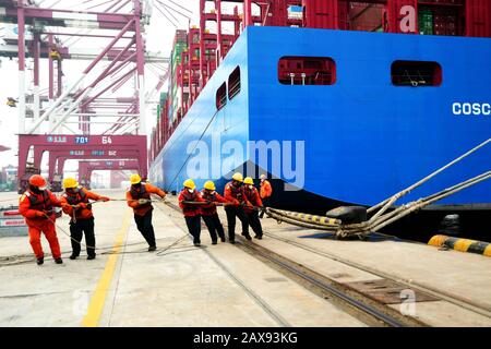 Les travailleurs portuaires amarent un navire à conteneurs sur un quai au port de Qingdao, dans la ville de Qingdao, dans la province de Shandong, en Chine orientale, le 11 février 2020. Banque D'Images