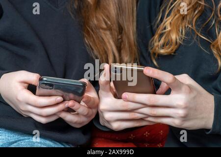 les adolescentes étant des cyber-mensonges ou se contentant de rattraper sur les médias sociaux, à la fois sur les téléphones, l'espace de copie au niveau de la main ci-dessus Banque D'Images