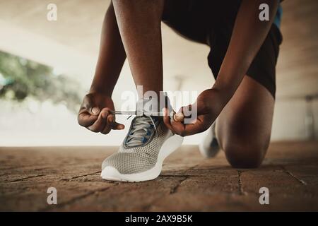 Mains mâles attachant la lacets des chaussures de course avant la pratique Banque D'Images