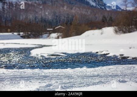 Piste de neige au premier plan avec toile de fond une rivière de montagne, des montagnes alpines et une cabane de montagne. Mise au point sélective, flou. France Banque D'Images