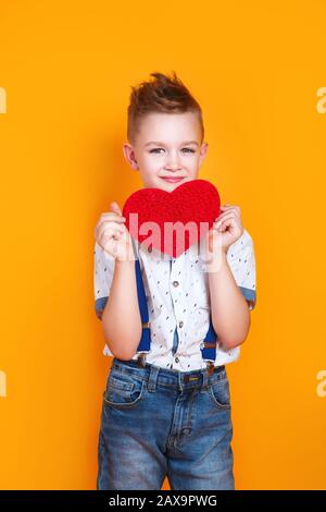 Enfant avec cœur rouge sur fond jaune. Fête de la mère. Saint Valentin Banque D'Images